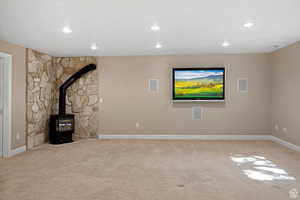 Unfurnished living room featuring carpet flooring and a wood stove