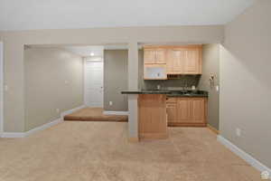 Kitchen with light carpet, light brown cabinetry, and sink