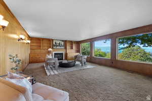 Carpeted living room featuring wood walls, built in features, and a textured ceiling