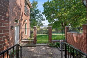 View of gate with a lawn and a patio