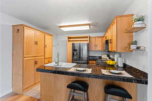 Kitchen with a kitchen breakfast bar, sink, light hardwood / wood-style flooring, kitchen peninsula, and stainless steel appliances