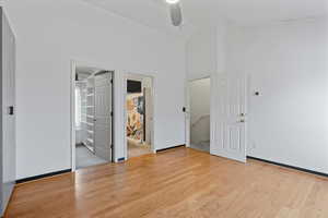 Empty room with ceiling fan, high vaulted ceiling, and light hardwood / wood-style floors