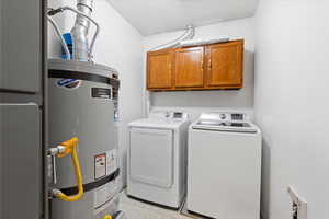 Laundry room featuring washer and dryer, cabinets, and water heater