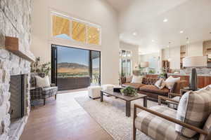 Living room featuring a mountain view, light hardwood / wood-style floors, a fireplace, and high vaulted ceiling