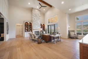 Living room featuring beamed ceiling, high vaulted ceiling, a healthy amount of sunlight, and light hardwood / wood-style flooring