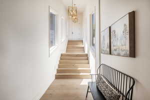 Stairs with wood-type flooring and an inviting chandelier