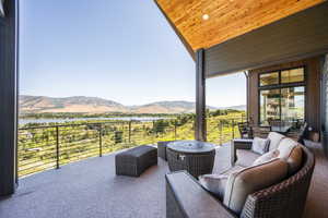 View of patio featuring a water and mountain view, a balcony, and an outdoor hangout area