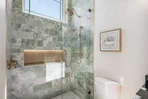 Bathroom featuring tiled shower and toilet