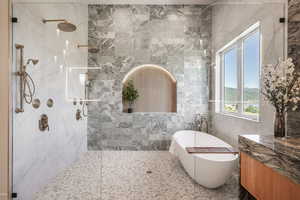 Bathroom featuring shower with separate bathtub and tile walls