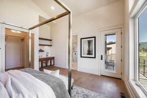 Bedroom featuring access to exterior, light hardwood / wood-style flooring, high vaulted ceiling, and multiple windows