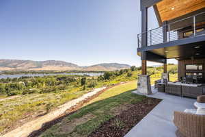 View of yard featuring a patio, a balcony, an outdoor hangout area, and a water and mountain view