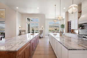 Kitchen featuring decorative backsplash, decorative light fixtures, light stone countertops, and a spacious island