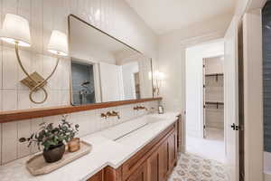 Bathroom with vanity, a shower, backsplash, tile patterned flooring, and tile walls