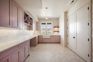 Kitchen with backsplash, sink, decorative light fixtures, and light brown cabinets