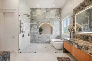 Bathroom with vanity, separate shower and tub, and tile walls