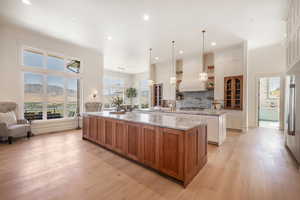 Kitchen featuring white cabinetry, light stone countertops, hanging light fixtures, a mountain view, and a spacious island