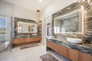 Bathroom with vanity, a tub to relax in, and tile walls