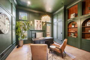 Interior space with built in shelves, plenty of natural light, a notable chandelier, and light hardwood / wood-style flooring