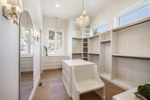 Walk in closet featuring light hardwood / wood-style flooring and an inviting chandelier