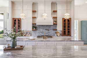 Kitchen featuring backsplash, light stone countertops, and pendant lighting