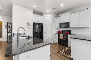 Kitchen featuring white cabinets, sink, dark hardwood / wood-style floors, and black appliances