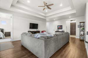 Living room with dark hardwood / wood-style flooring, a tray ceiling, and ceiling fan