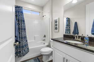 Full bathroom featuring hardwood / wood-style floors, vanity, toilet, and shower / bath combo with shower curtain