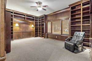 upstairs second bedroom / office room with carpet flooring, custom wooden bookshelves, and ceiling fan