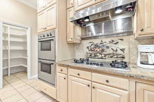 Kitchen featuring light tile patterned floors, stainless steel appliances, tasteful backsplash, and ornamental molding