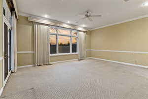 Carpeted primary bedroom with ceiling fan and ornamental molding. View of golf course.