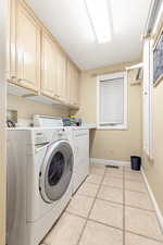 Laundry room with light tile patterned flooring, and cabinets