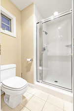 Primary bathroom featuring tile patterned flooring, toilet, and walk in shower