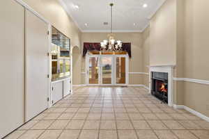 formal dining area featuring a gas fireplace, light tile patterned floors, a chandelier, and ornamental molding. Golf course view.