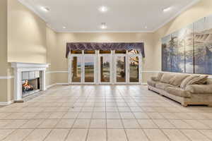 Formal living room featuring a gas fireplace, light tile patterned flooring, and ornamental molding. View of golf course