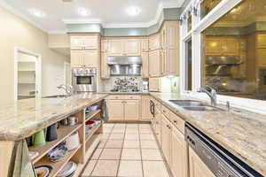 Kitchen featuring light cabinetry, sink, ornamental molding, and appliances with stainless steel finishes