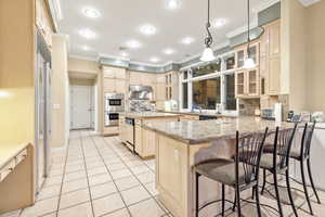 Kitchen featuring light stone countertops, kitchen peninsula, decorative light fixtures, decorative backsplash, and a breakfast bar