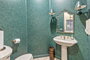 1/2 Bathroom on first floor featuring tile patterned floors, toilet, and sink