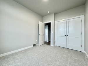 Unfurnished bedroom with light colored carpet and a closet