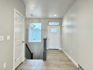 Doorway to outside featuring light hardwood / wood-style flooring and an inviting chandelier