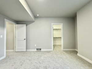 Unfurnished bedroom with light colored carpet, a spacious closet, and a closet