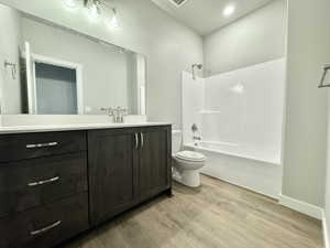 Full bathroom featuring bathing tub / shower combination, vanity, wood-type flooring, and toilet