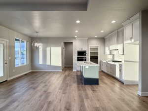 Kitchen featuring decorative backsplash, appliances with stainless steel finishes, sink, a center island with sink, and hanging light fixtures