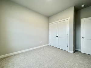 Unfurnished bedroom featuring light carpet and a closet