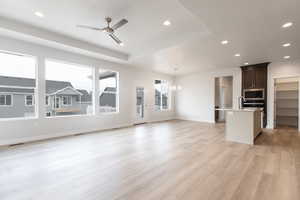 Unfurnished living room with ceiling fan with notable chandelier, light hardwood / wood-style flooring, and sink