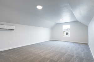 Bonus room with carpet flooring, vaulted ceiling, and an AC wall unit