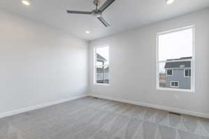 Carpeted spare room featuring ceiling fan