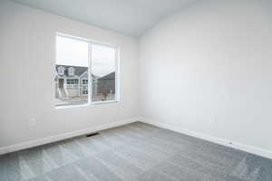 Unfurnished room featuring carpet flooring and lofted ceiling