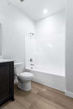 Full bathroom with hardwood / wood-style floors, vanity, toilet, and shower / tub combination