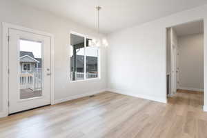 Unfurnished dining area with light hardwood / wood-style floors and a notable chandelier