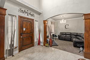 Foyer entrance with a notable chandelier, light colored carpet, and ornamental molding